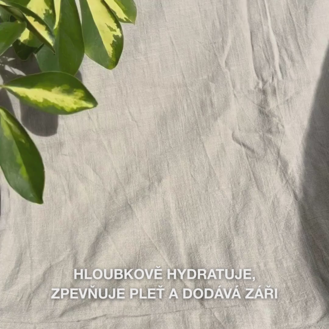 Detailní záběr ženy, která nanáší zářivě růžovou Vitamin B12 Kollagenovou pleťovou masku na čistou pleť: uhlazuje ji na tvářích, čele a bradě, čímž kolagen a B12 hýčkají, hydratují, zpevňují pokožku a zanechávají ji rozjasněnou a uklidněnou.